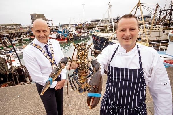 Mayor of Ards and North Down, Councillor Mark Brooks with Paul Mercer, Deputy Head of School of Hospitality, Management, Tourism and Languages at SERC., holding a lobster at Portavogie Harbour.